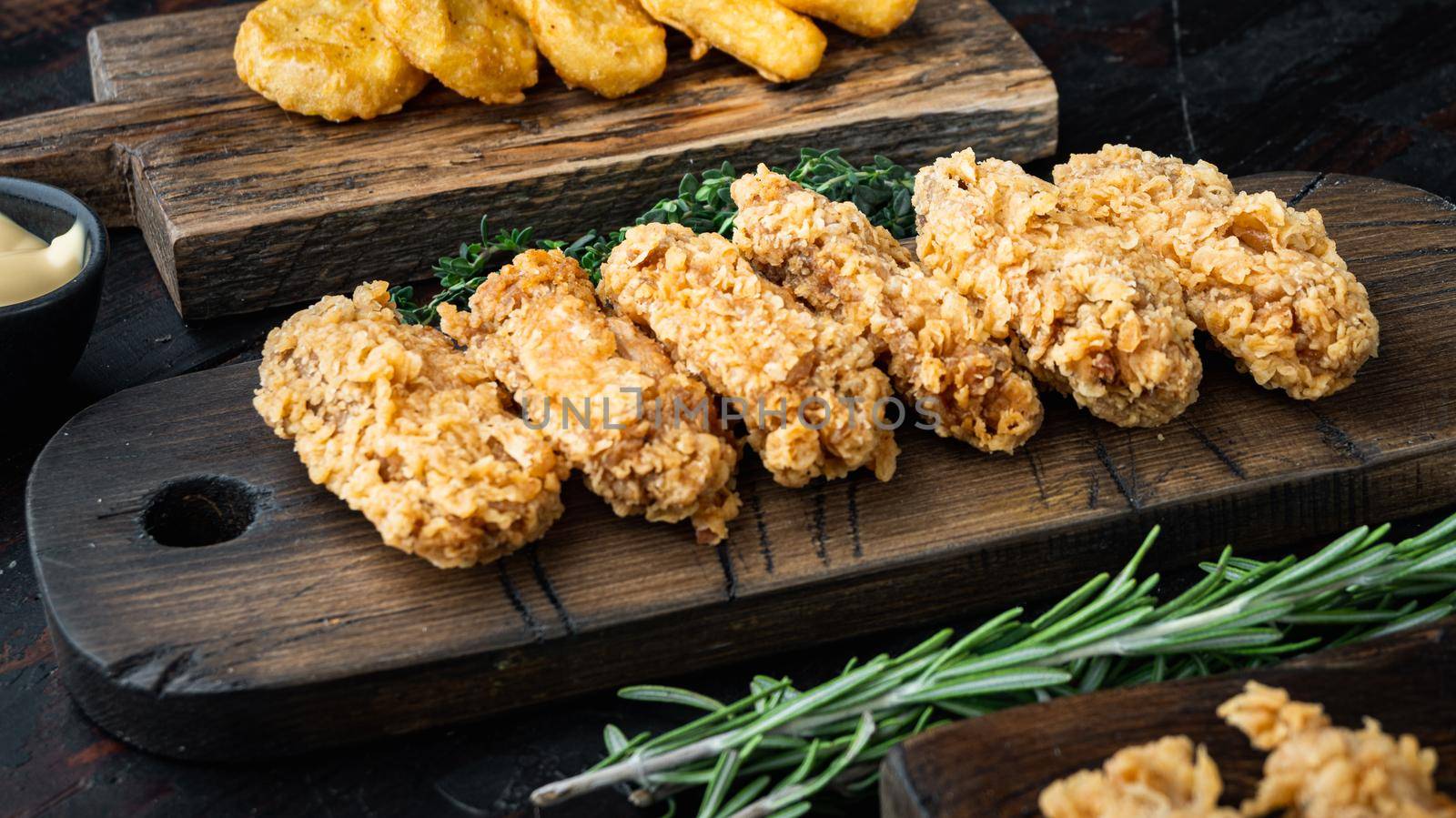 Breaded chicken wings cuts on old dark wooden table.
