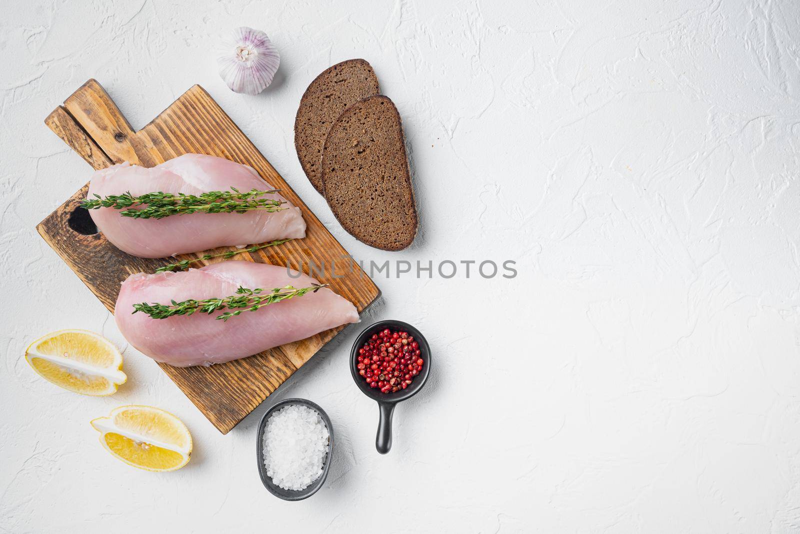 Crumbed uncooked chicken breasts ingredient on white background, flat lay with space for text
