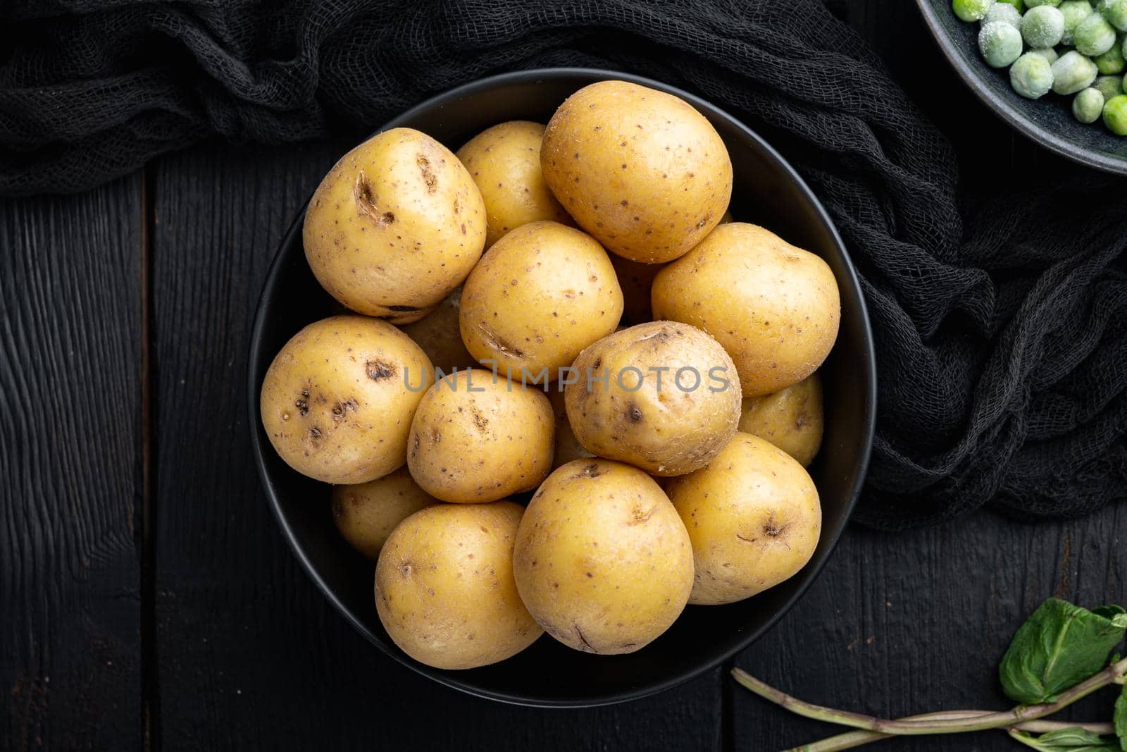 Pile of baby potatoe, top view, on black wooden background