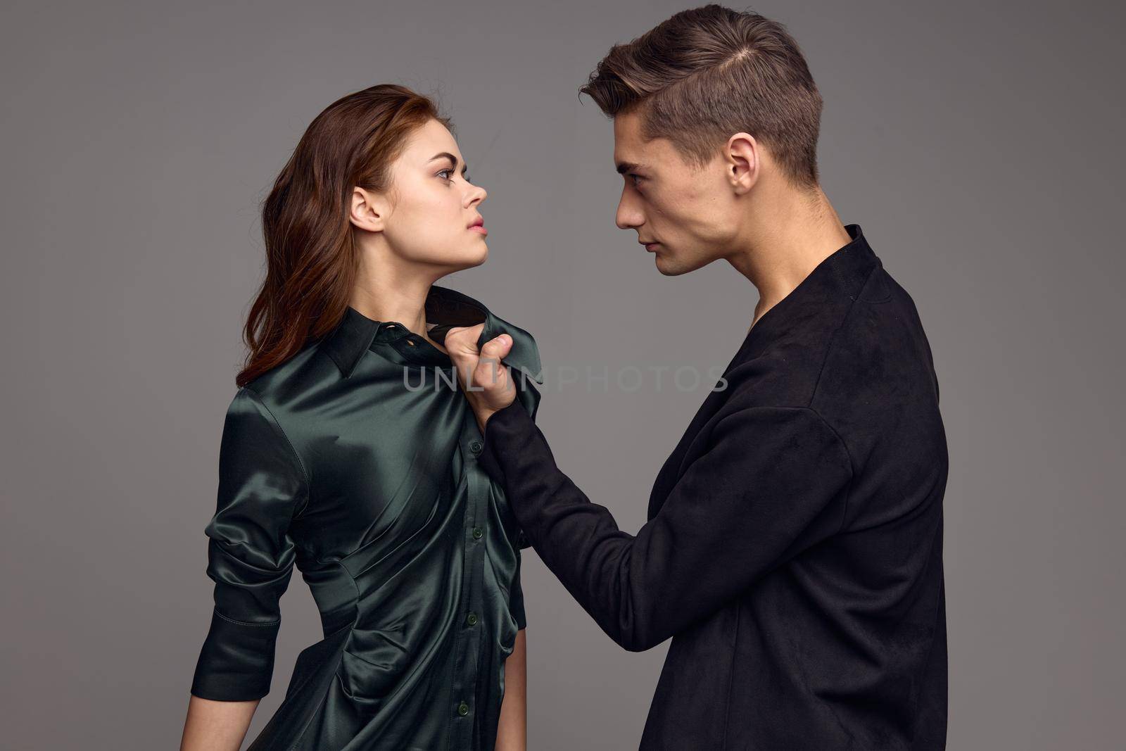 A frightened woman in a dress is looking at an aggressive man on a gray background by SHOTPRIME