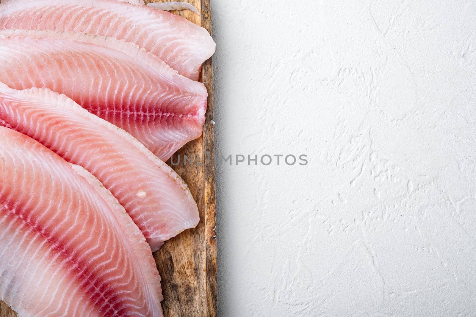 Tilapia fish, skinless meat, on white background, top view with copy space for text