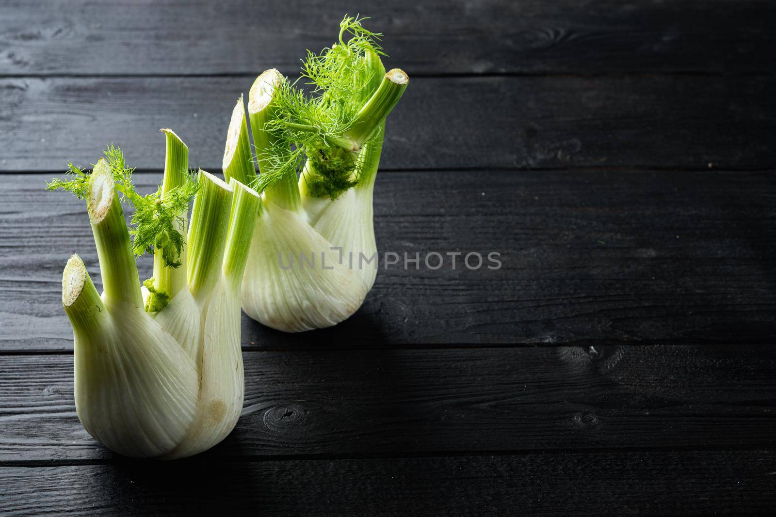 Fennel bulbs, on black wooden table with space for text