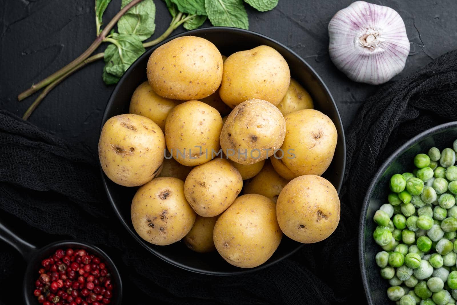 Fresh unpeeled, baby potatoes, top view, on black textured background