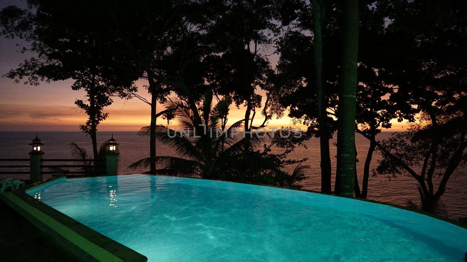 Incredible views of the pool and sunset. The bright colors of the setting sun and the orange sea. Turquoise water in the pool. Large palm leaves and trees as shadows. Lights are on. Relax. Koh Chang