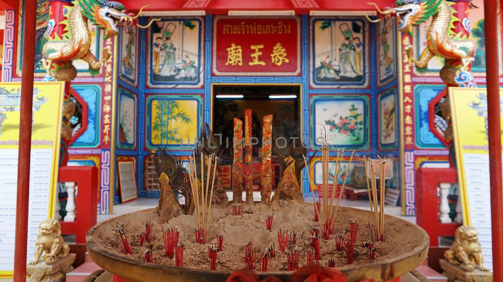 Chinese temple on Koh Chang island of Thailand. Bright colors of the temple, dragon and elephant sculptures. Flowers all around. The smoke from the sticks is coming. Hieroglyphs on the walls of bell.