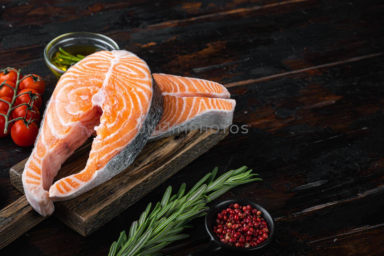 Salmon steak raw fish with herbs, on old wooden table.