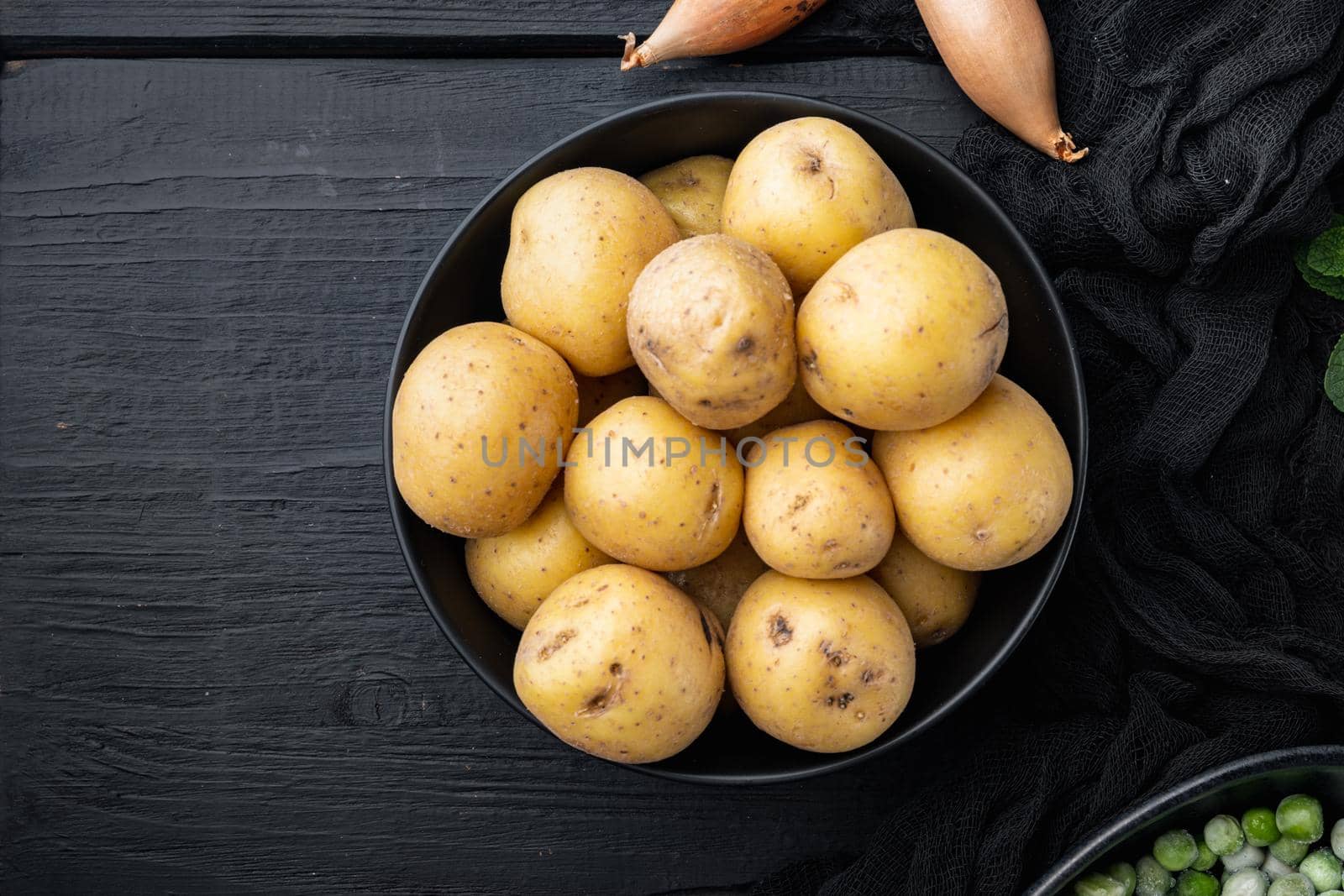Pile of baby potatoe, flat lay, on black wooden background with space for text