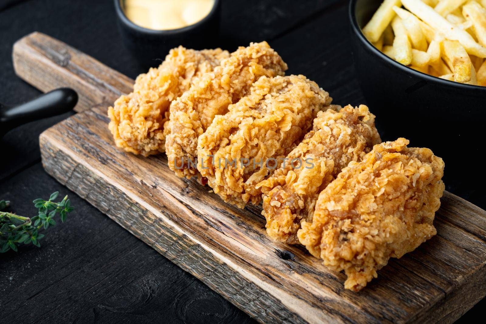 Fried chicken wings parts on black wooden table.