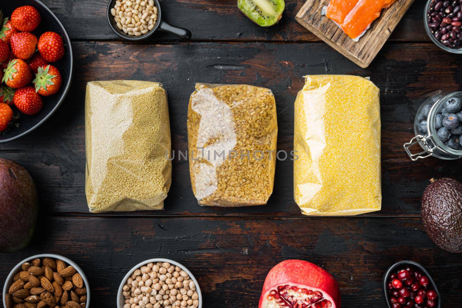 Couscous, bulgur and polenta packaged, flat lay on dark wooden background.