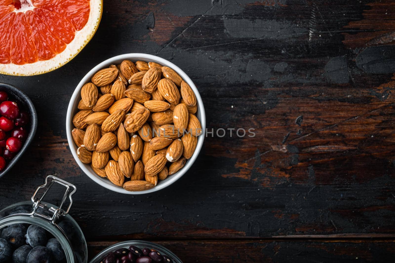 Almonds nuts in bowl, top view on dark wooden background, with copy space.