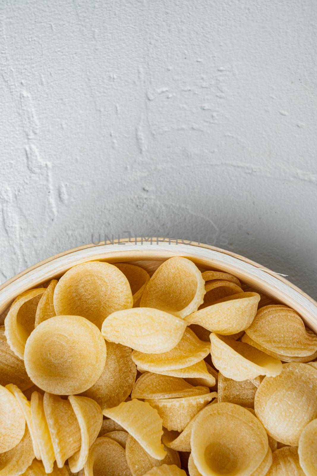Dried pasta shells in bowl, on white background, top view with copy space for text