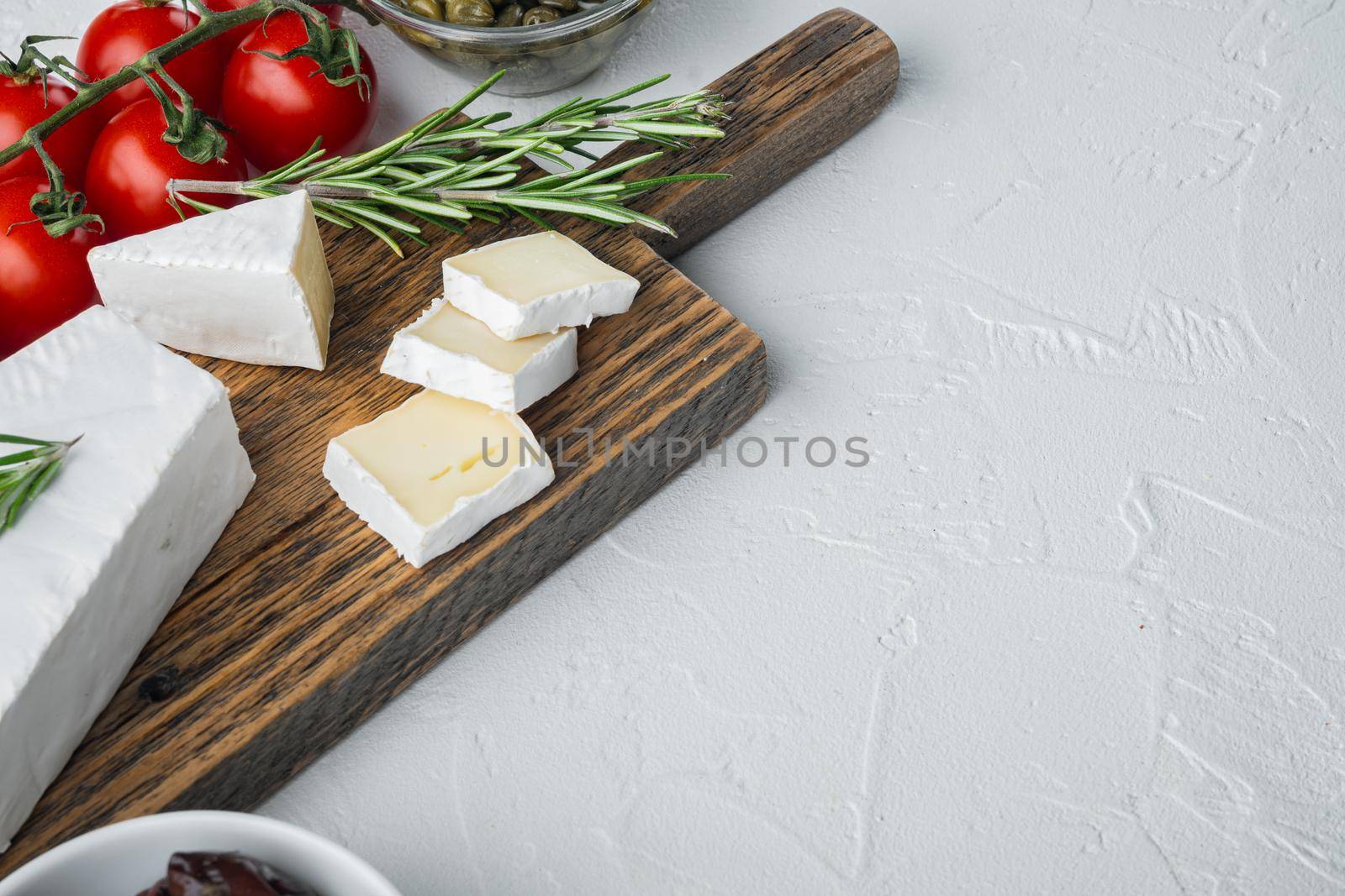 Antipasti platter with fresh cheese, bread and olive, on white background with copy space for text