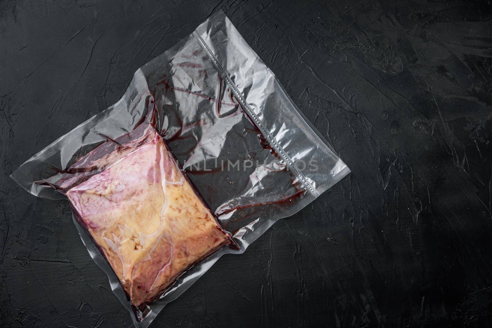 Top sirloin beef big cut in plastic pack, on black background, top view, with copy space for text