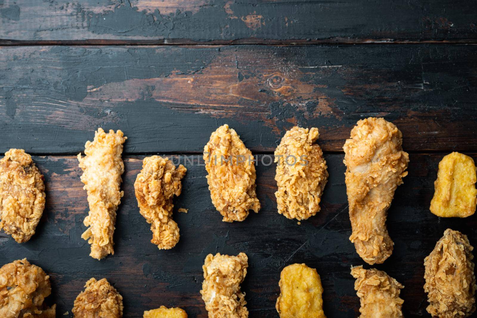 Crispy fried chicken parts on old dark wooden table, top view, with copy space.