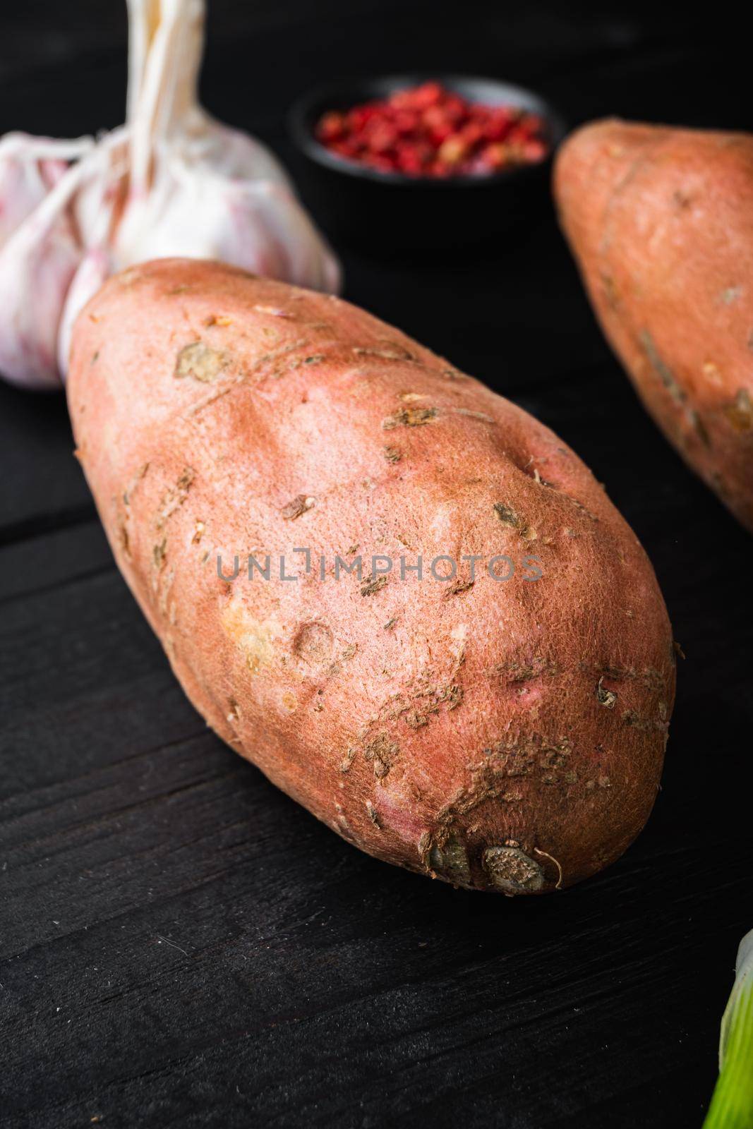 Sweet potato or batat with ingredients, on black wooden background.