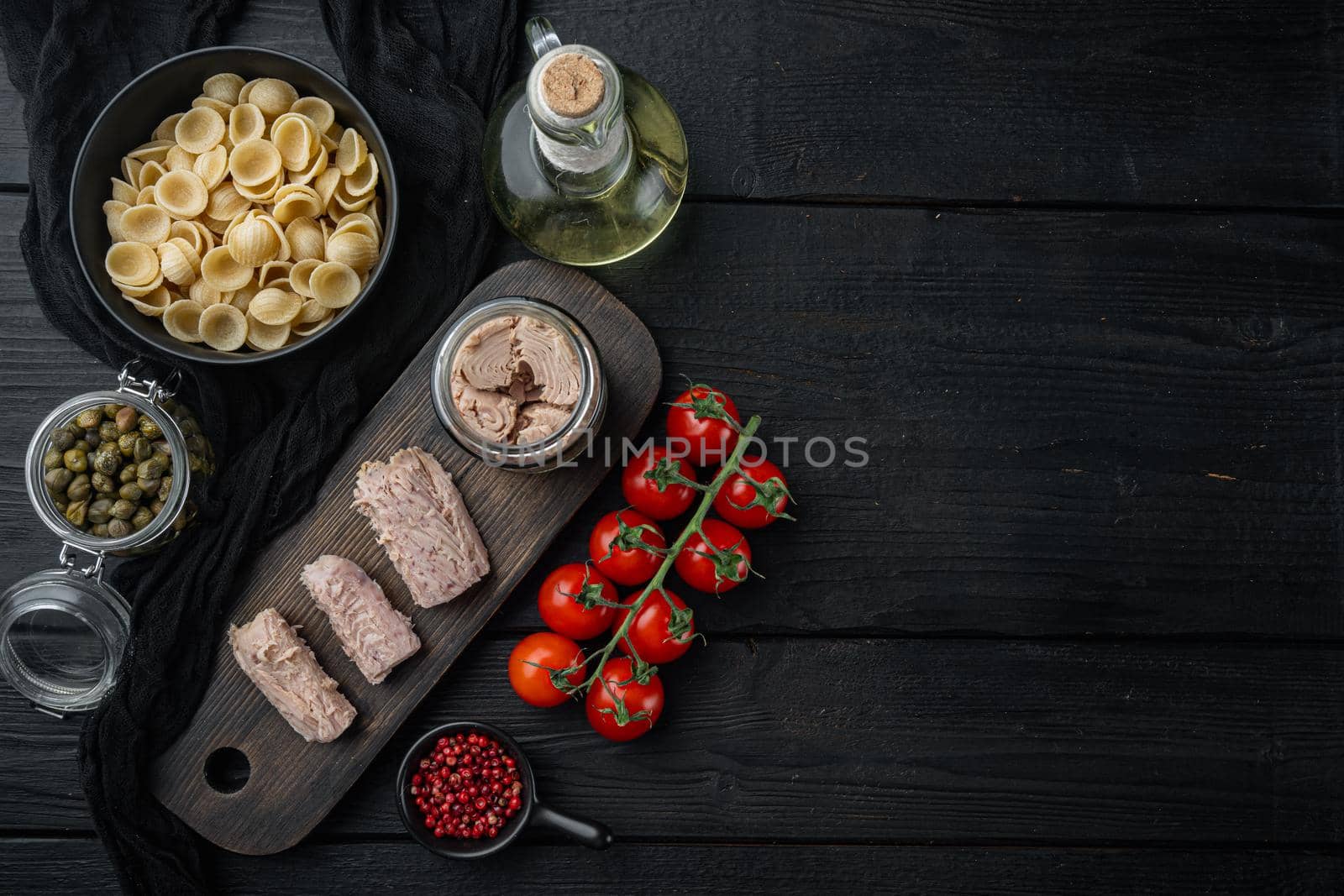 Tuna salad with pasta and vegetables ingredient, on black wooden table, flat lay with copy space for text