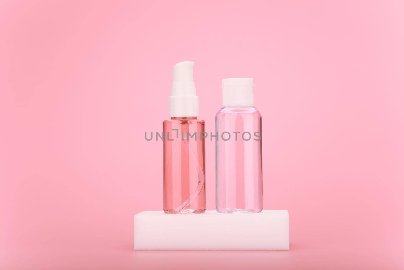 Cleaning foam or gel and moisturizing skin lotion in transparent bottle on white podium against bright pink background by Senorina_Irina