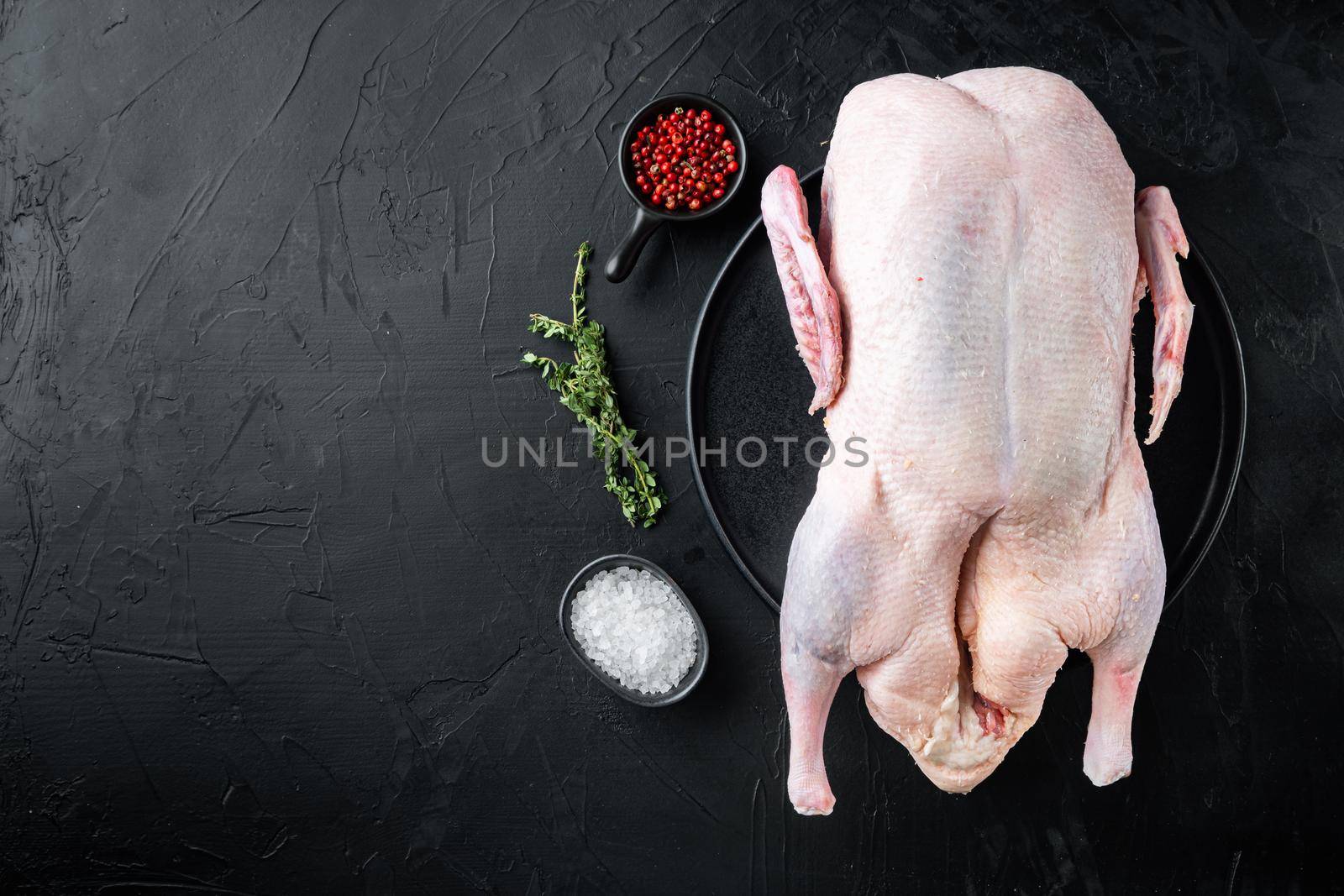 Raw whole farm duck meat on black background, top view, with copy space.