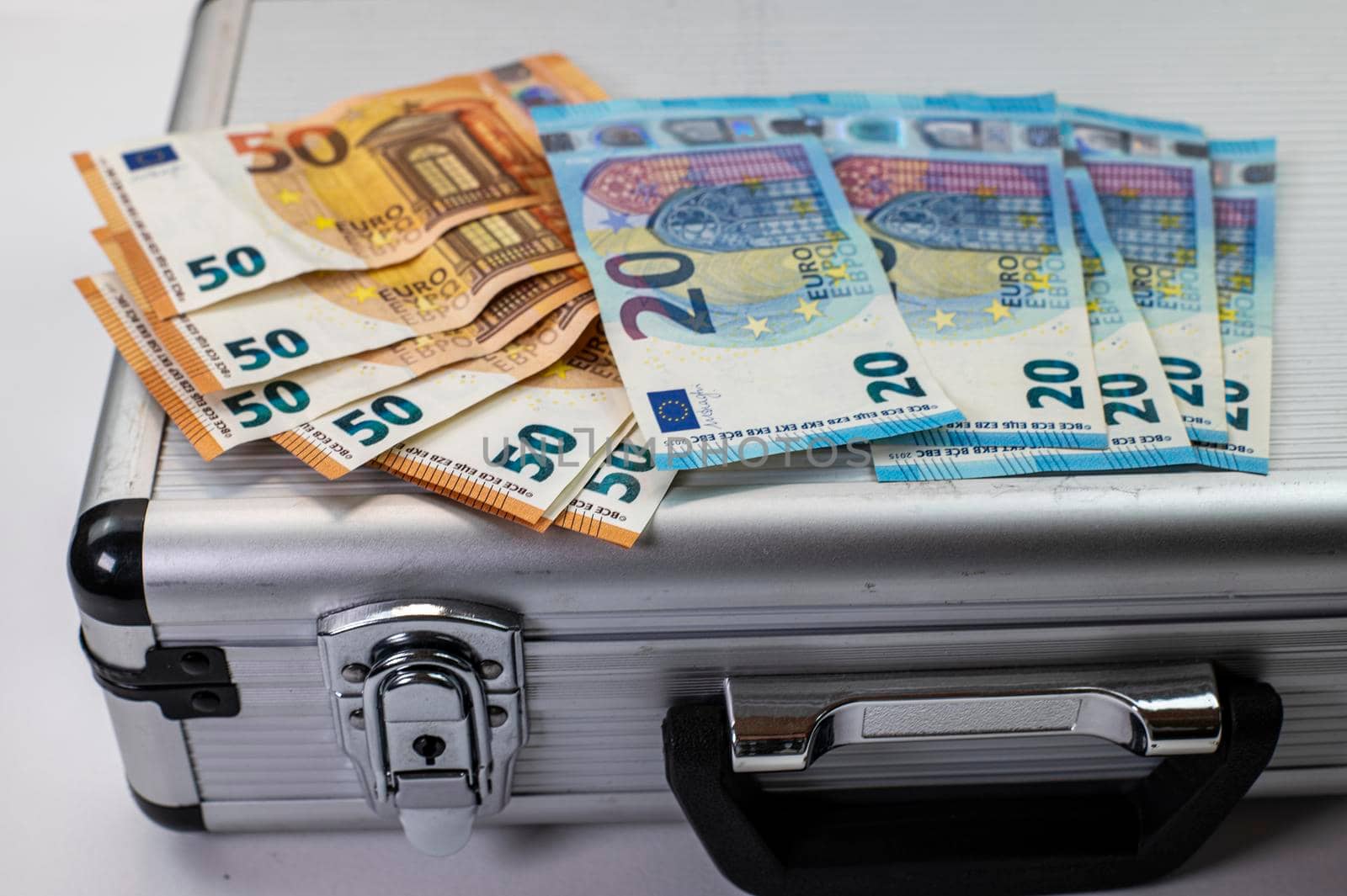 50 and 20 euro banknotes on aluminum briefcase on white background