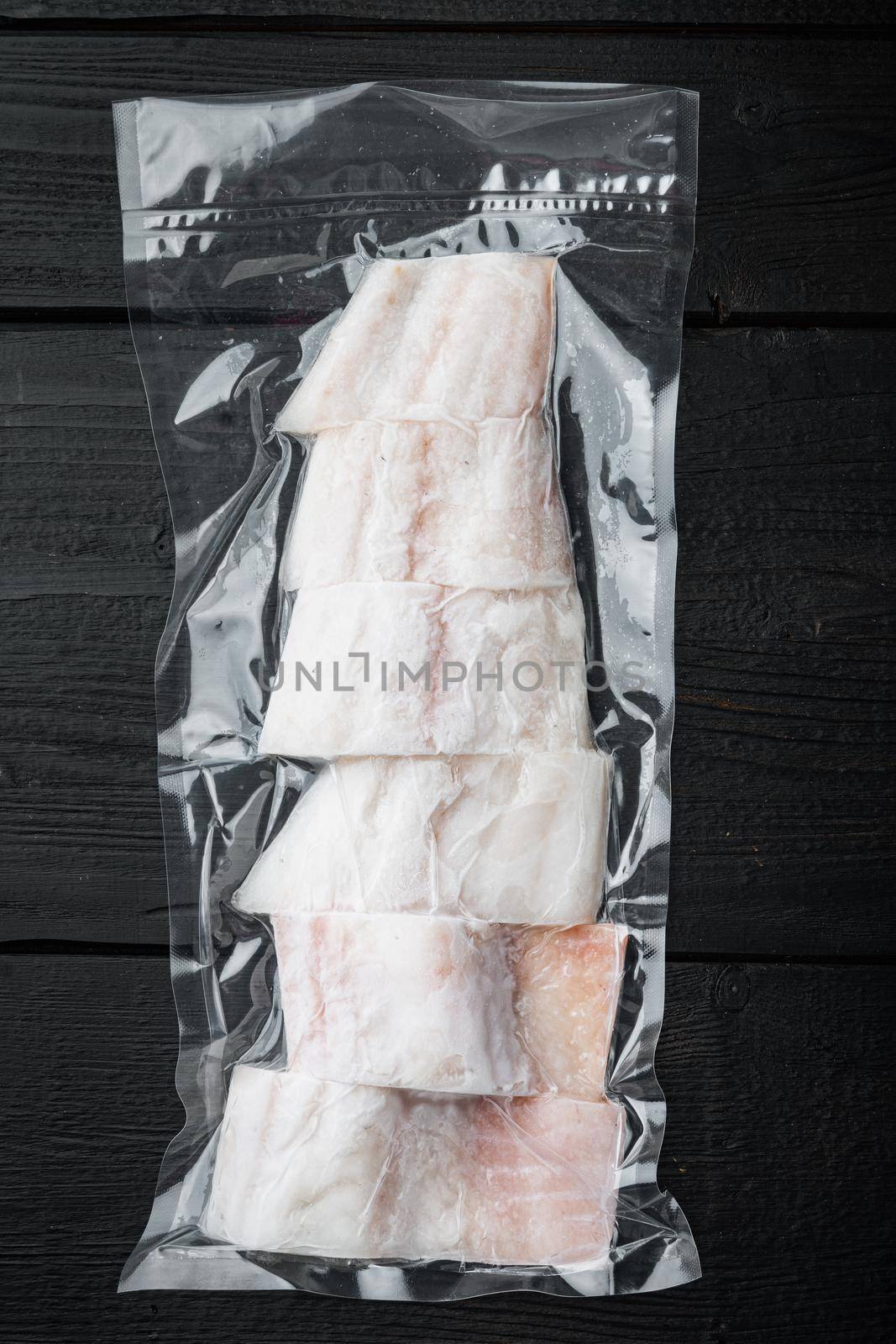 Haddock fish skinless in vacuum package, on black wooden table
