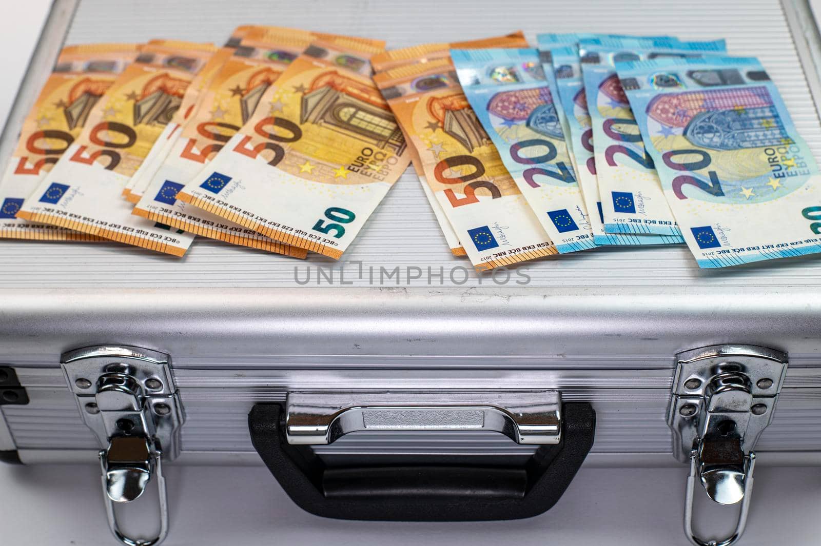 50 and 20 euro banknotes on aluminum briefcase on white background