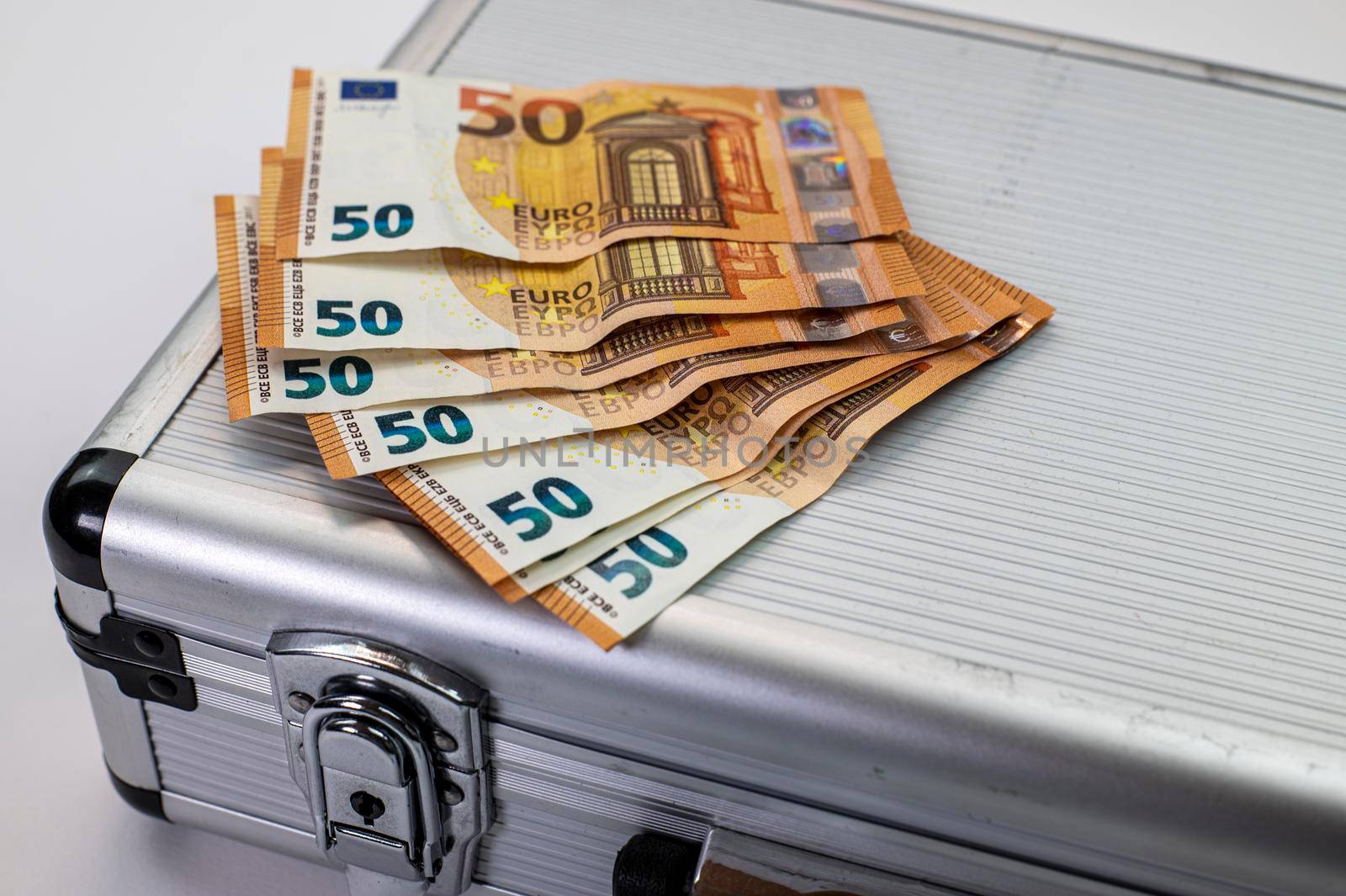 euro banknotes on aluminum briefcase on white background
