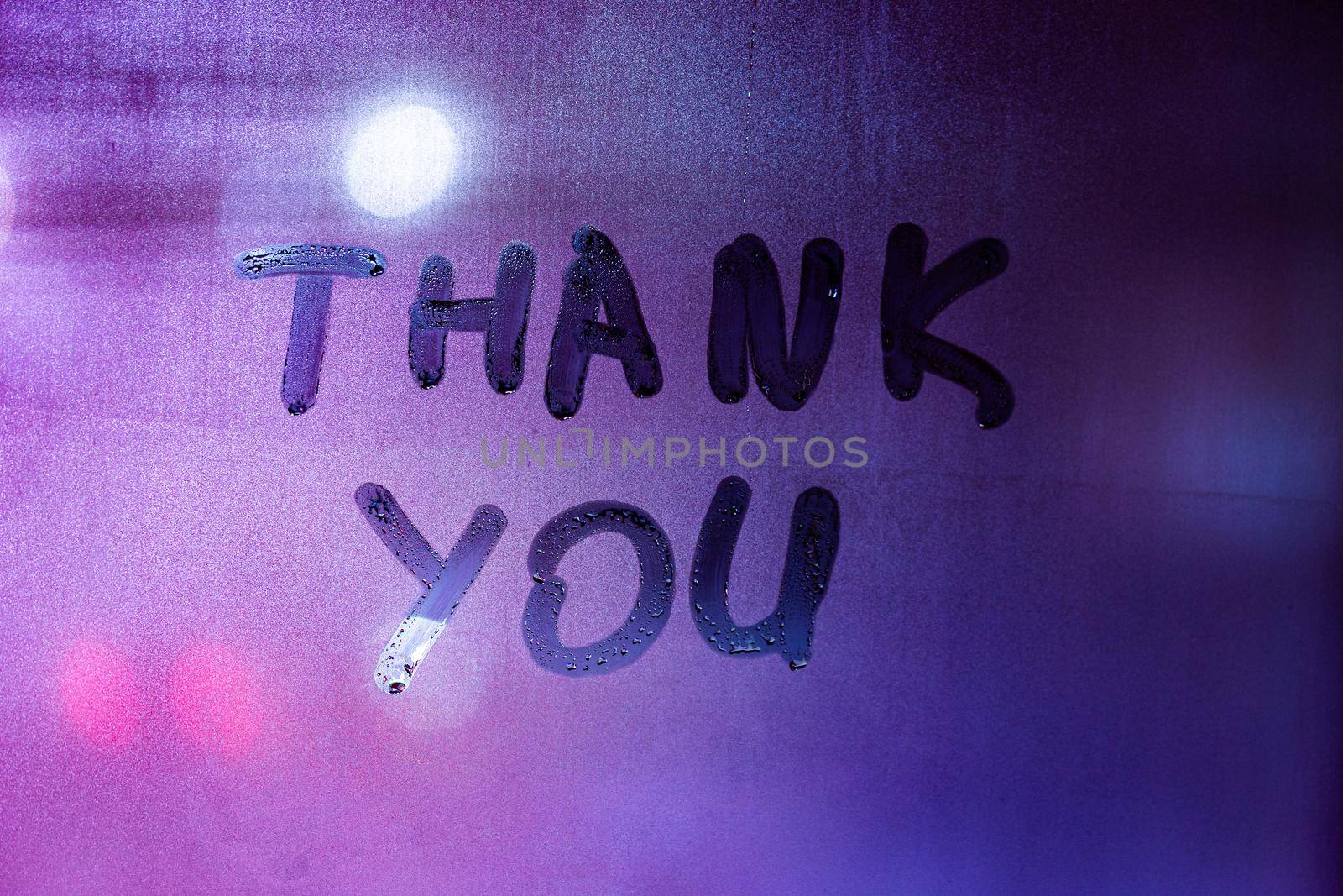 words thank you handritten on purple-blue night foggy window glass - closeup with selective focus by z1b