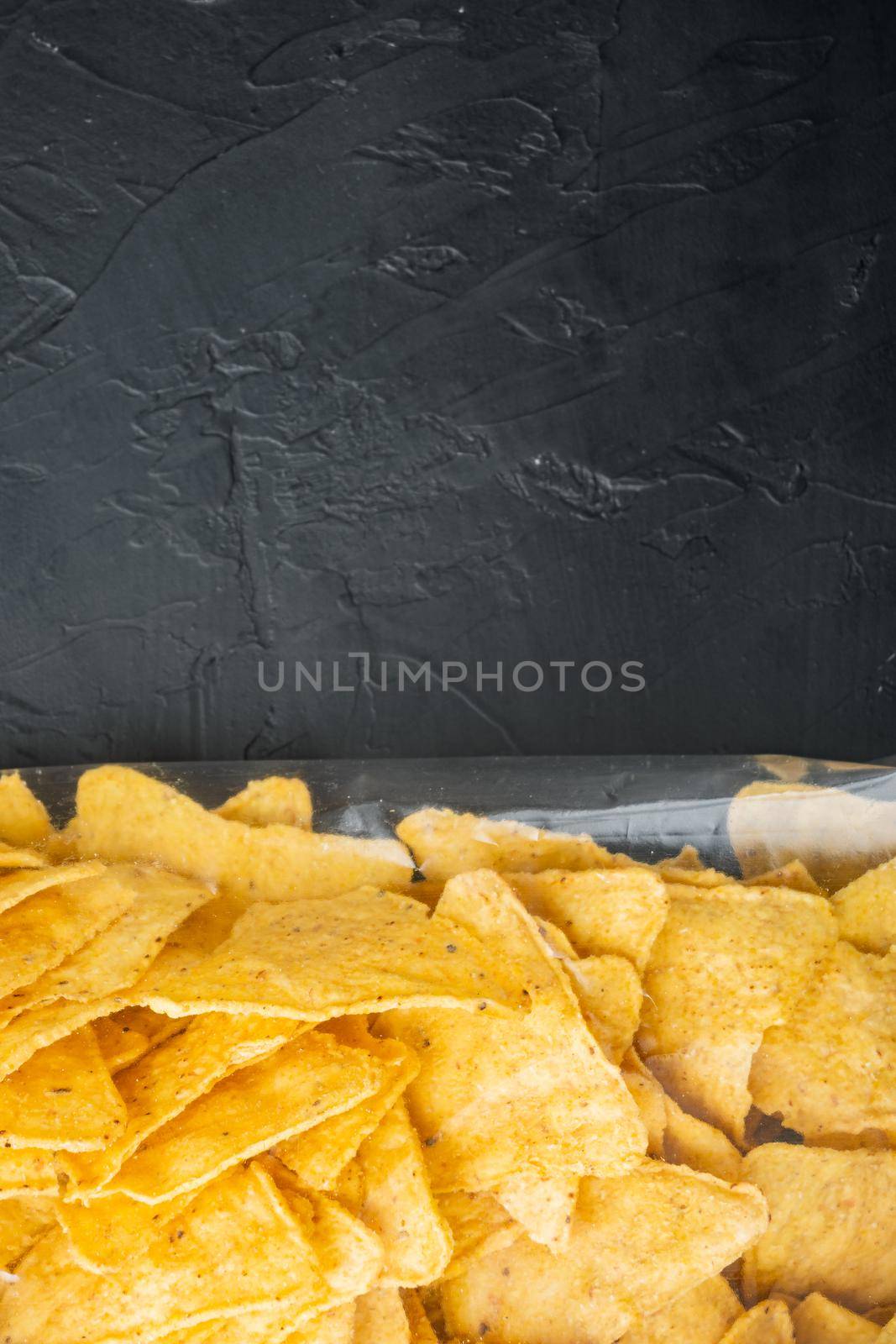 Nachos, triangle traditional Mexican corn appetizer pack, on black background, top view or flat lay with copy space for text