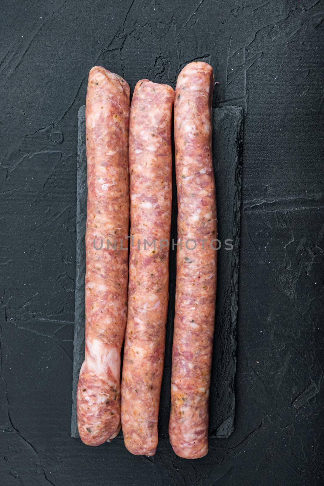 Homemade beef sausages, top view, on black background.