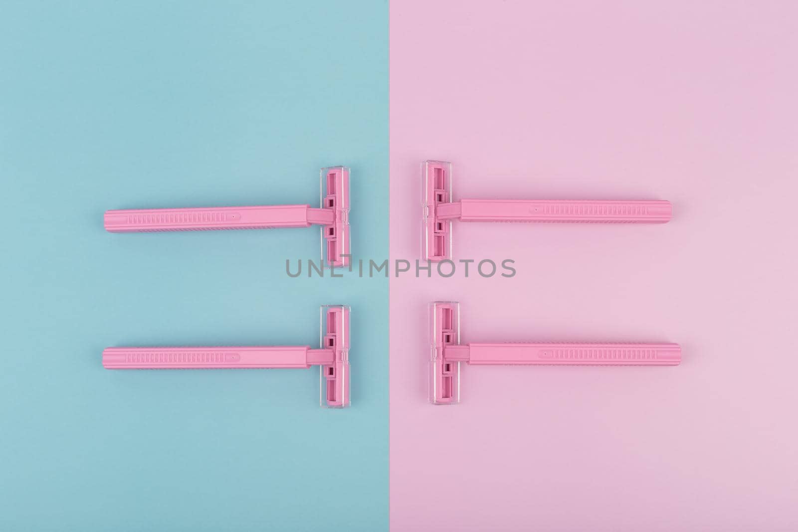 Flat lay with four pink plastic razors on pink and blue background by Senorina_Irina