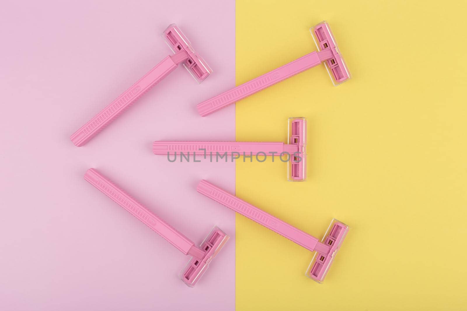 Top view of pink razors for shaving on colored duotone yellow and pink background by Senorina_Irina