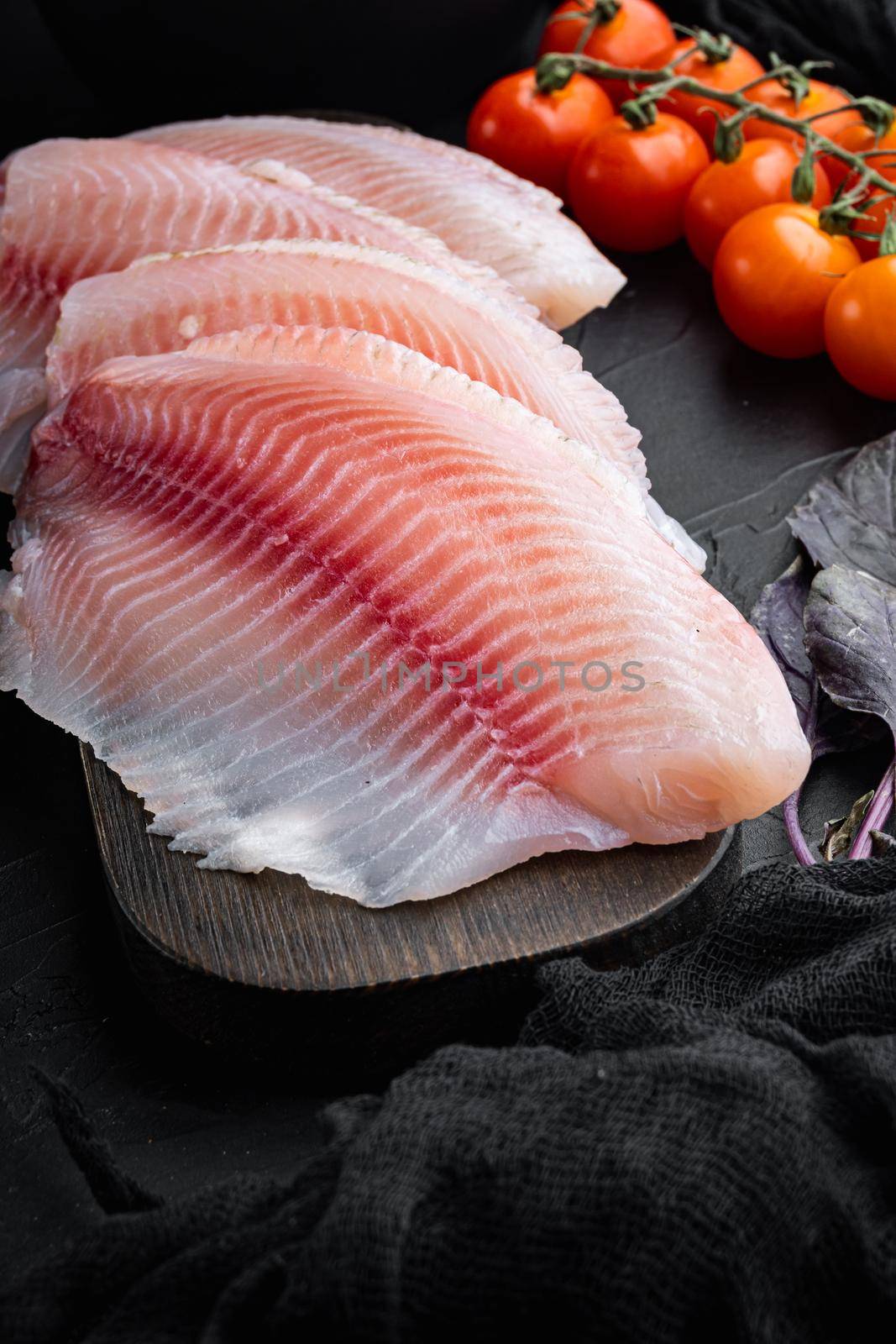 White fish fillet, with basmati rice and cherry tomatoes ingredients, on black background