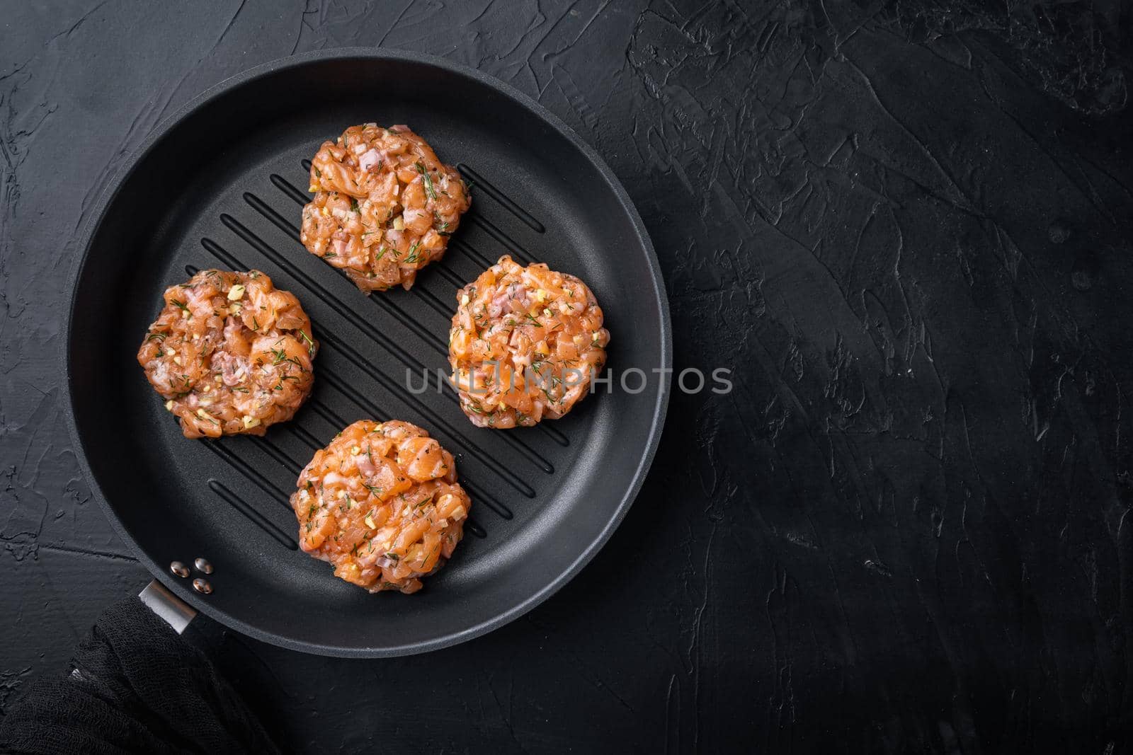 Raw quick asian salmon cutlet, on black textured background, top view with space for text