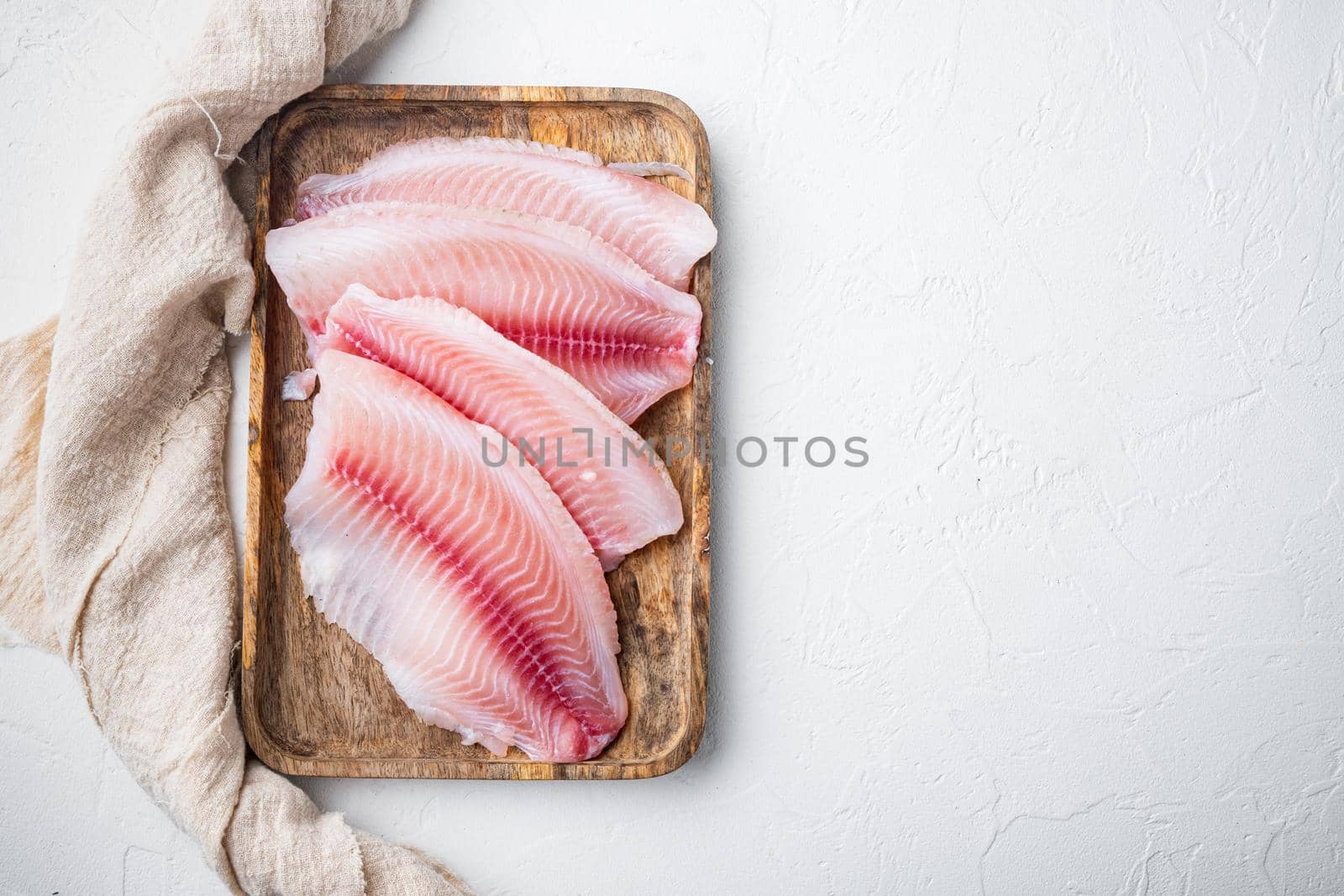 White tilapia fish fillet cuts on white background, top view with copy space for text