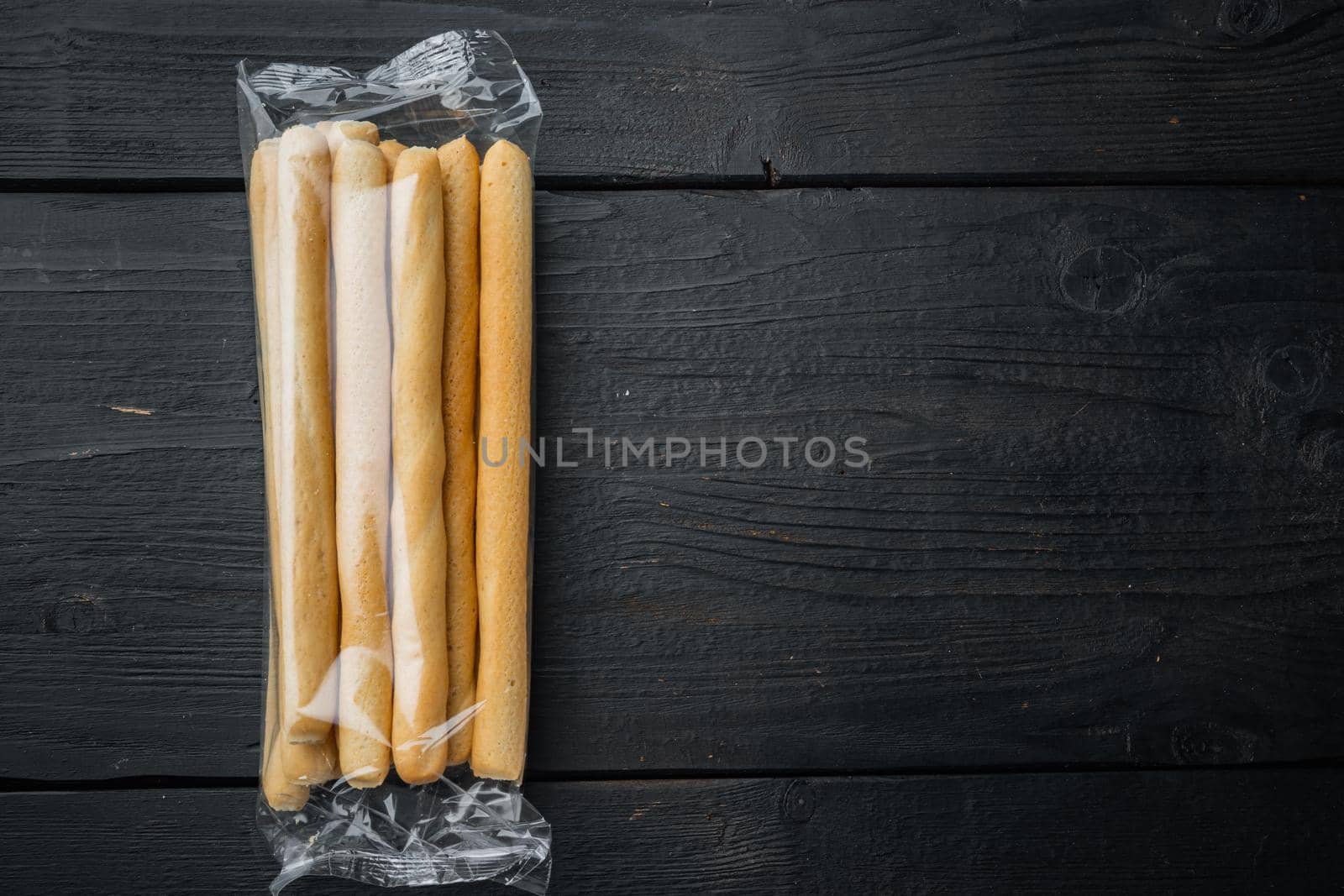 Grissini, with olive oil, on black wooden background, top view with copy space for text