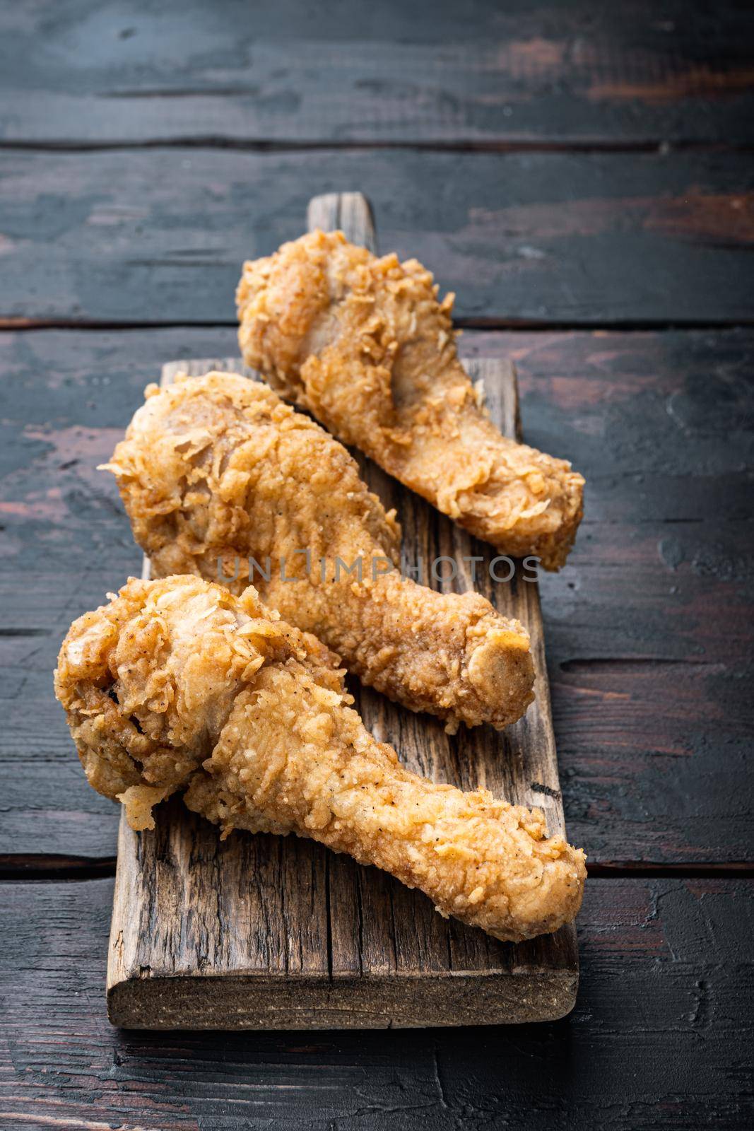 Breaded kentucky chicken drumctick parts on old dark wooden table.