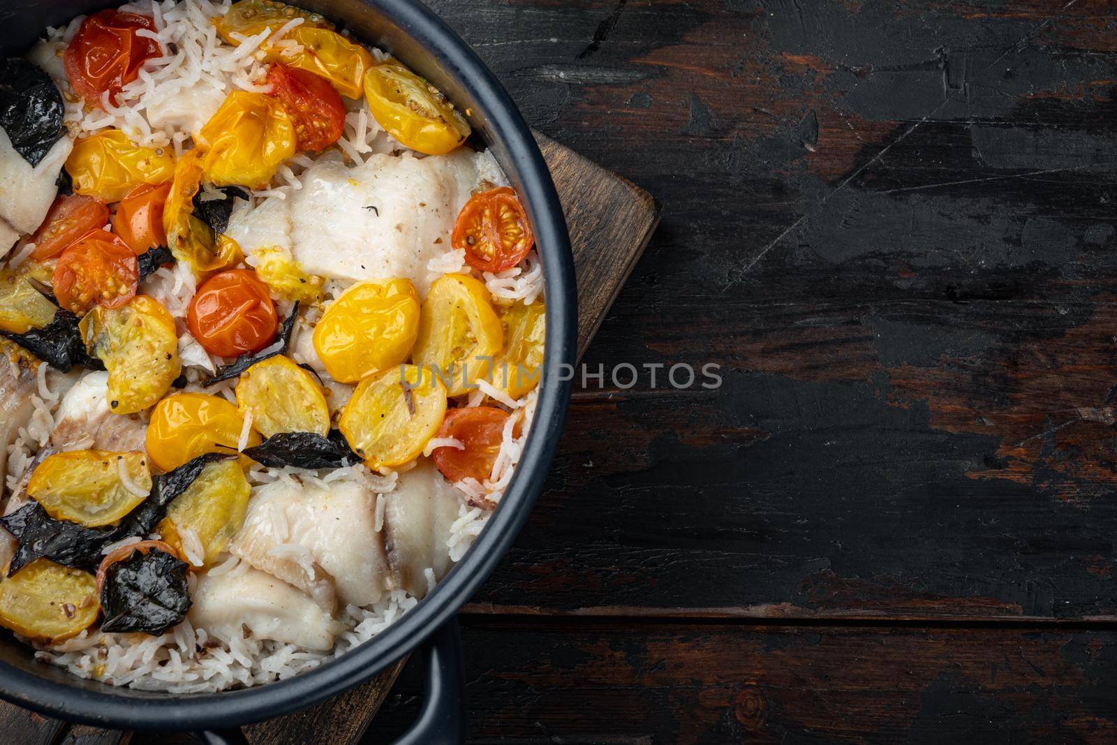 One pan fabulous fish, with basmati rice and cherry tomatoes, on old wooden table, top view with copy space for text