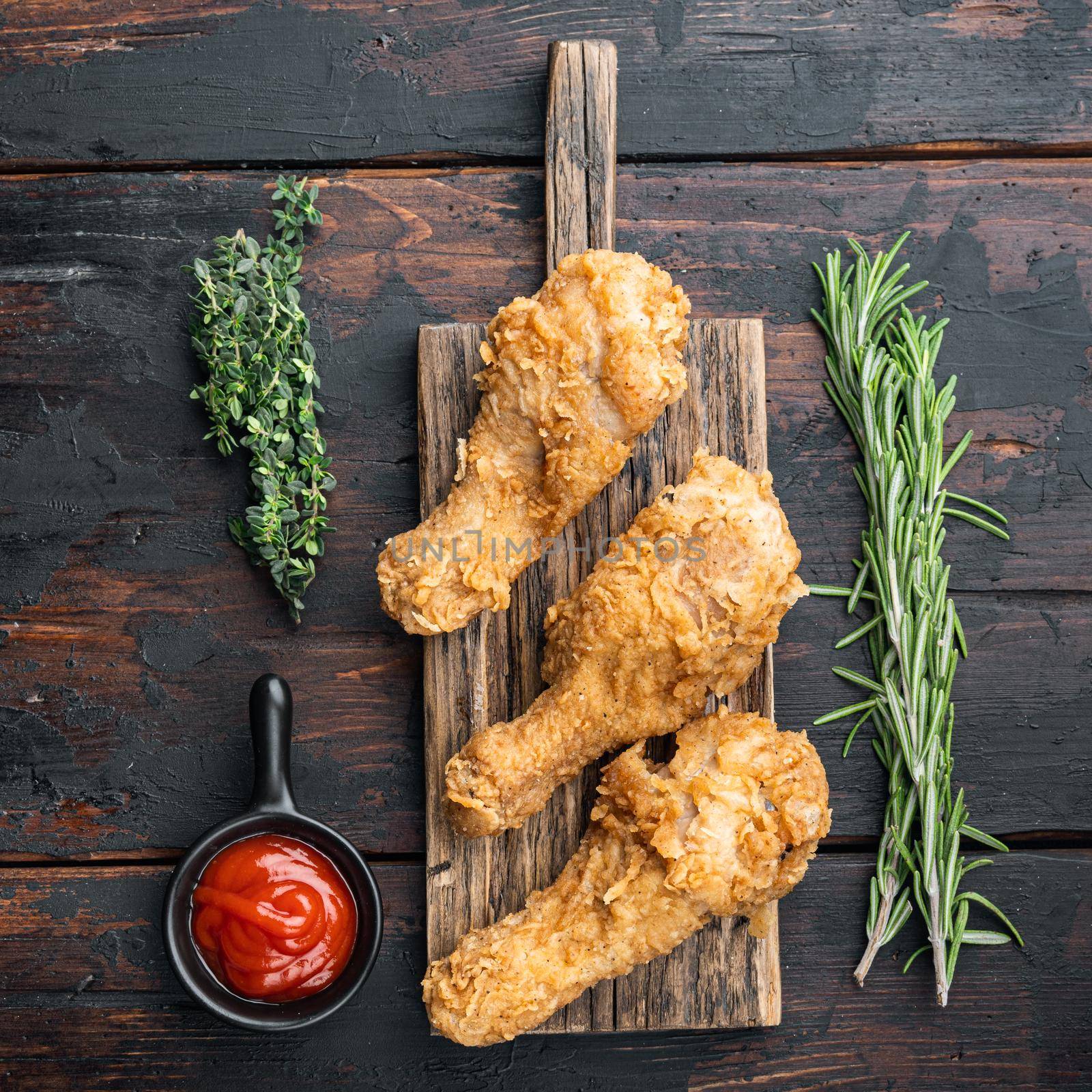 Breaded kentucky chicken drumctick parts on dark wooden background, flat lay.