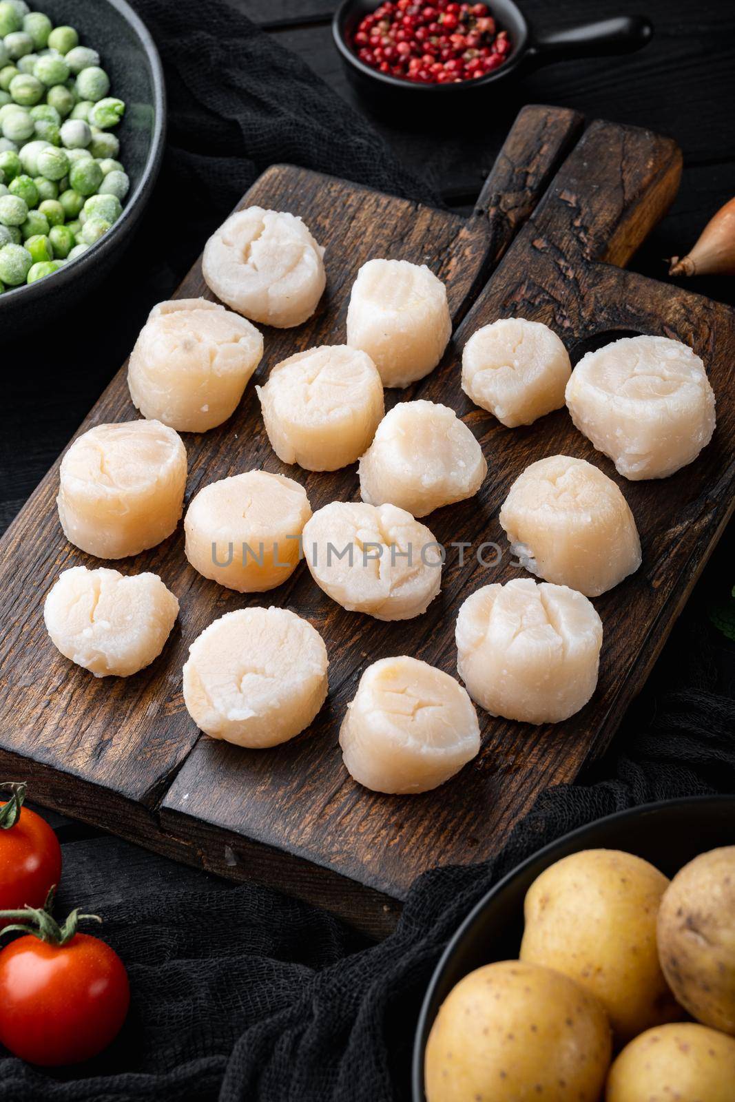 Fresh raw scallops ingredients ready for cooking, on black wooden background