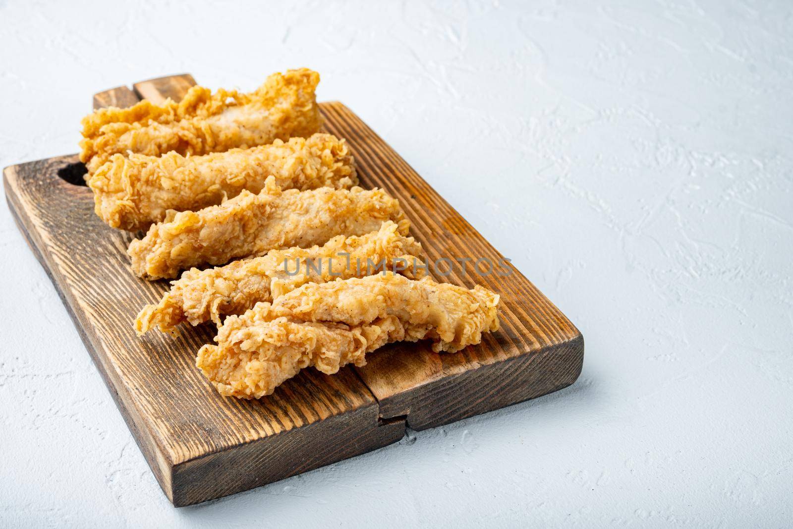 Fried crispy chicken stripes parts on white background.