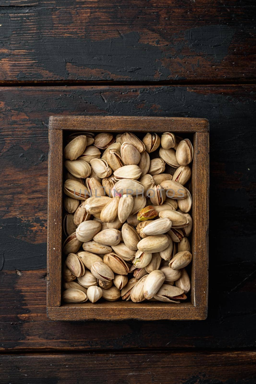 Shelled, unsalted pistachios, on old wooden table, flat lay