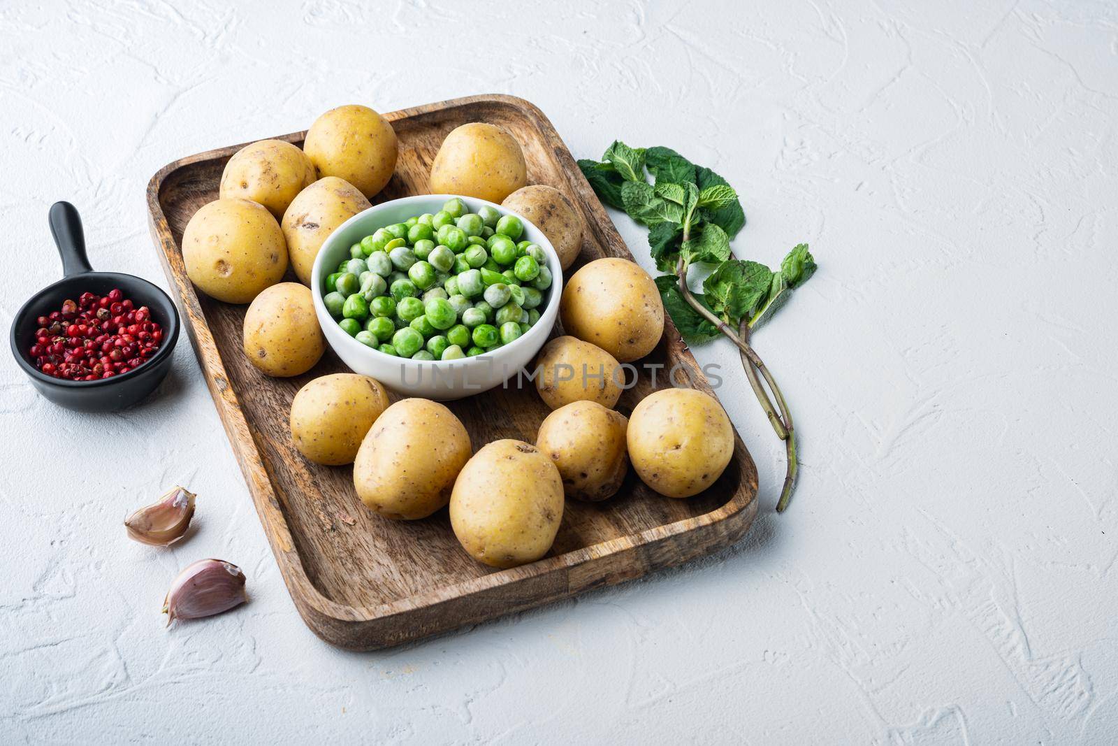 Mashed potatoes ingredient with green pea and mint, on white textured background with space for text