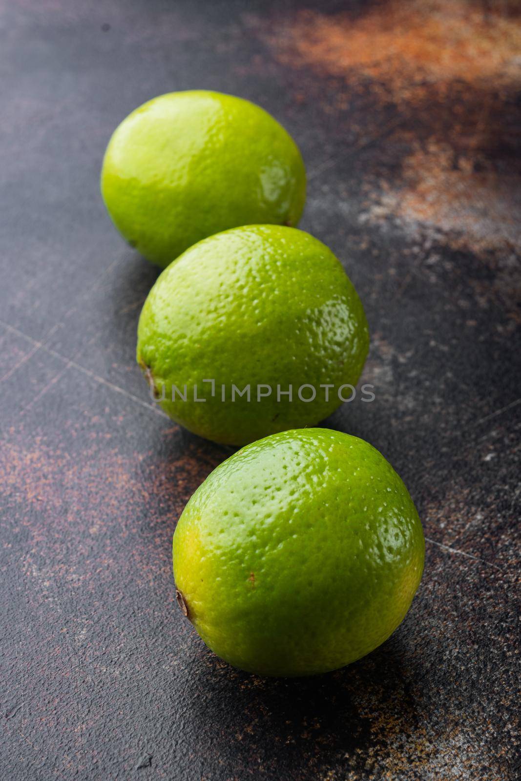 Whole green lime set, on old dark rustic background
