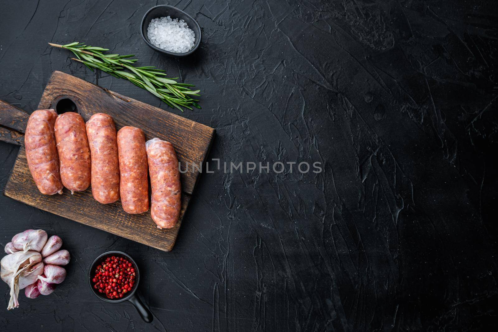 Raw organic pork sausages, top view with space for text, on black background.