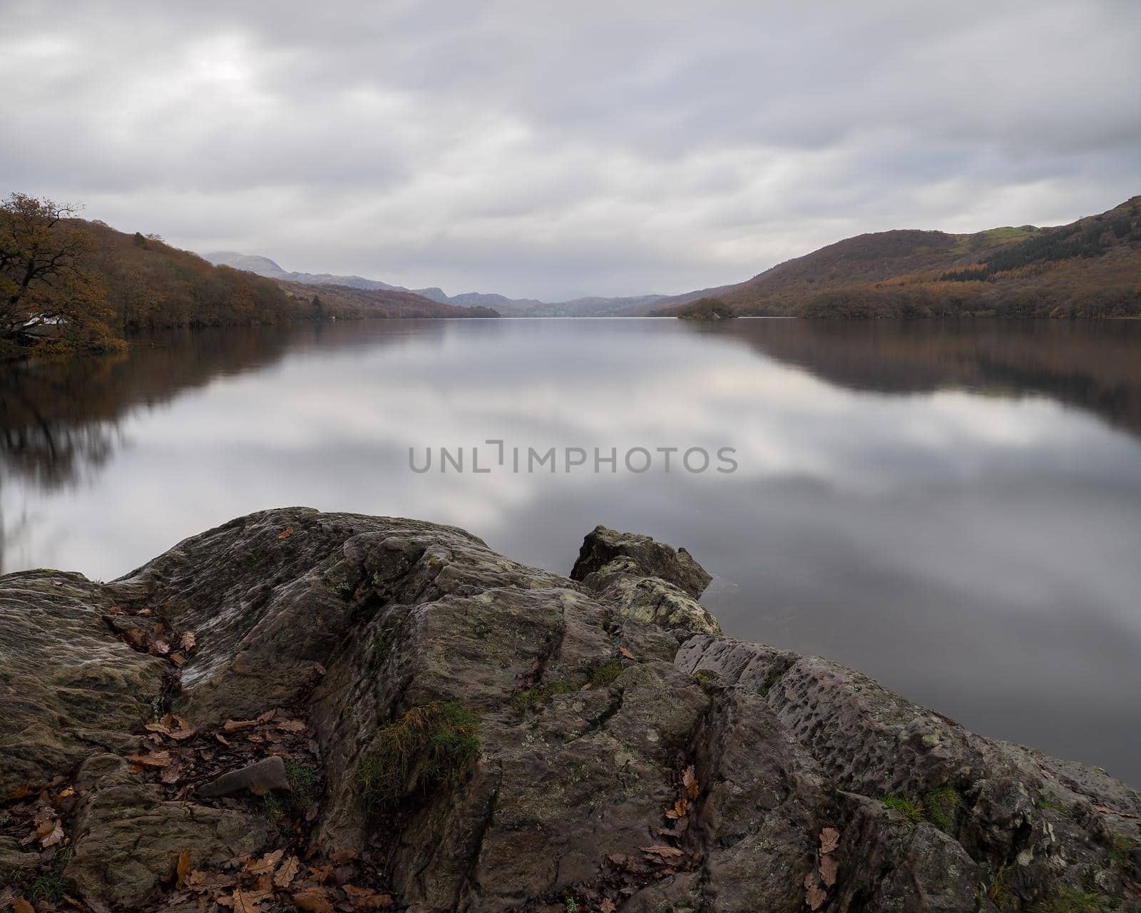 View over the calmness of Coniston Water with the fells in the background and clouds reflected in the water, Lake District, UK