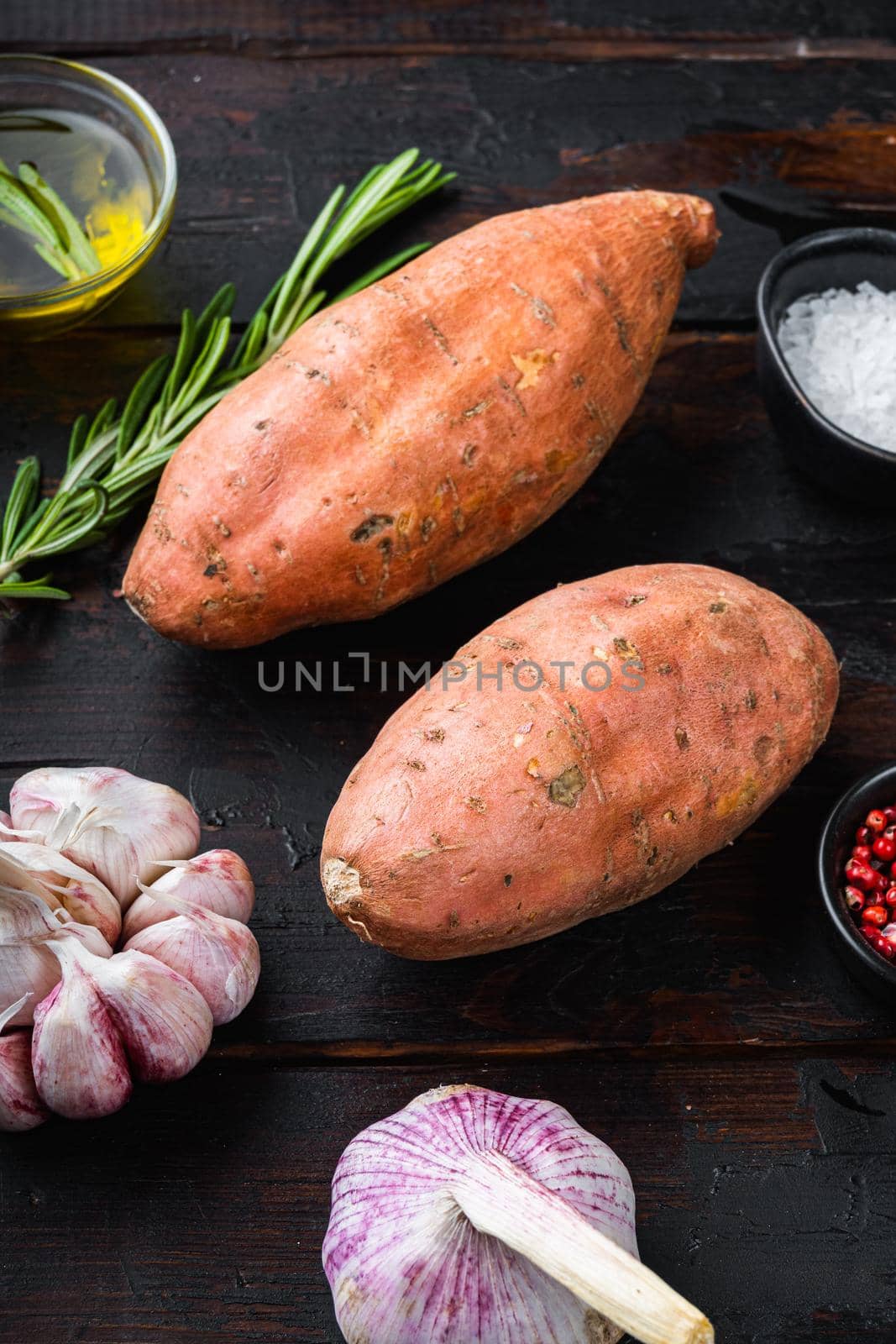 Sweet potato or batat with herbs on old wooden table, top view.