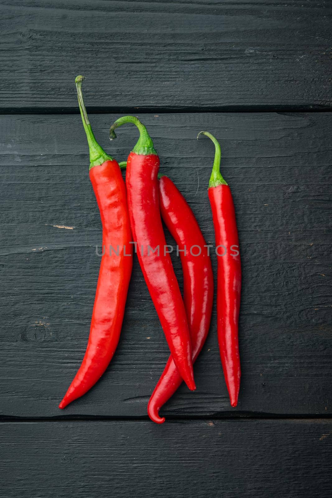 Whole red chili peppers set, on black wooden background, top view or flat lay