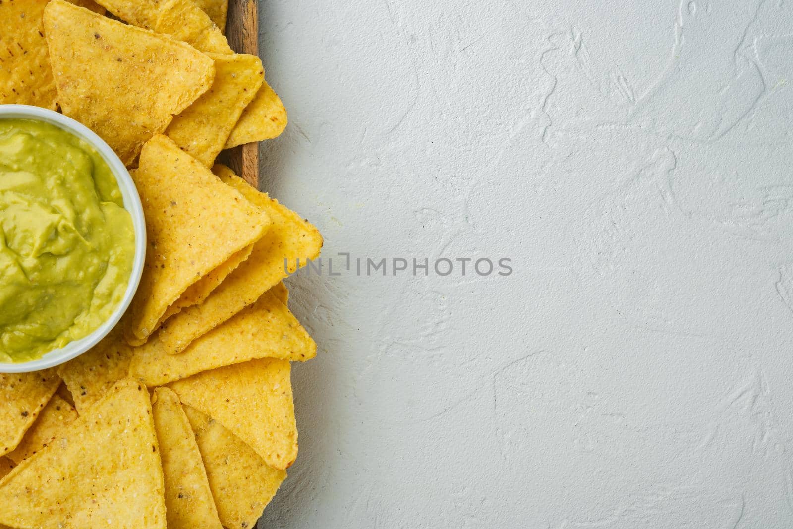 Mexican nachos chips with cheese and guacamole sauces, on white background, top view or flat lay with copy space for text