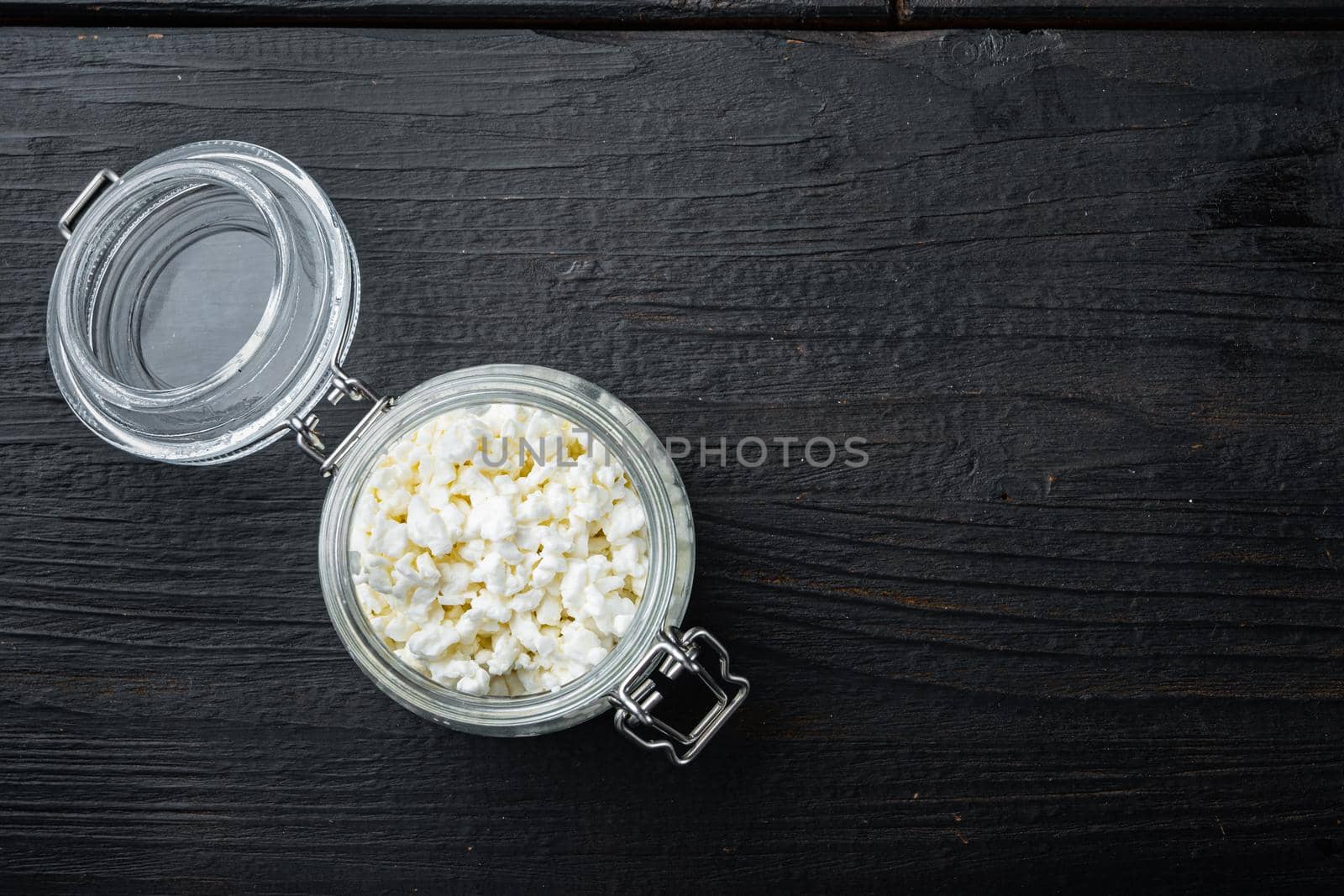 Cottage cheese, curd, on black wooden table, top view with space for text