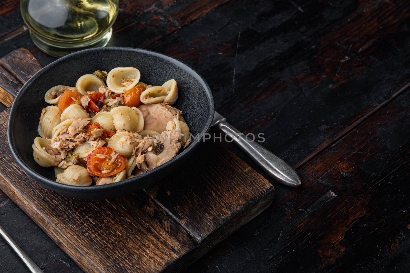 Pasta with vegetables and tuna in bowl, on dark wooden background with copy space for text